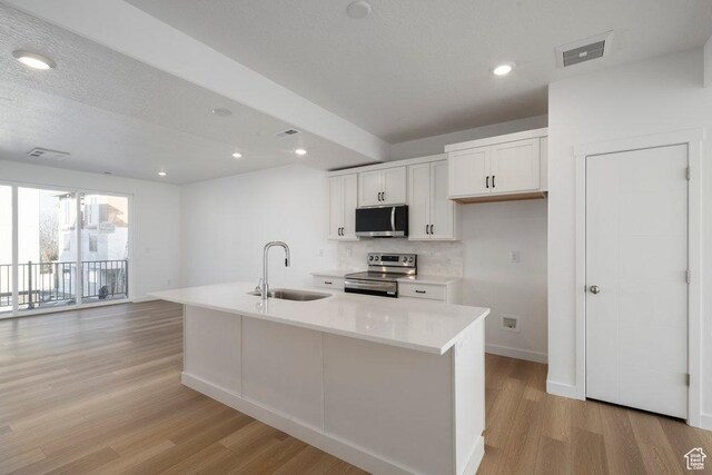 4119 S Winder Ward Dr E Unit 3-106, Millcreek, UT 84124 - kitchen featuring stainless steel appliances, a sink, light wood-style flooring, white cabinets, and backsplash