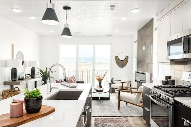 4119 S Winder Ward Dr E Unit 3-106, Millcreek, UT 84124 - kitchen with appliances with stainless steel finishes, a sink, light countertops, pendant lighting, and light wood-style floors