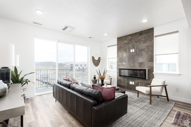 4119 S Winder Ward Dr E Unit 3-106, Millcreek, UT 84124 - living area with a tiled fireplace, light wood-style flooring, plenty of natural light, baseboards, and recessed lighting