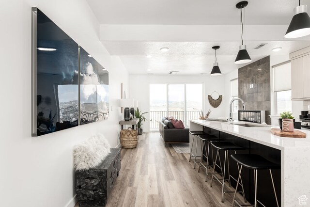 4119 S Winder Ward Dr E Unit 3-106, Millcreek, UT 84124 - kitchen with light countertops, modern cabinets, light wood-style flooring, white cabinetry, and a breakfast bar area
