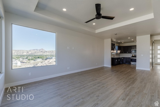 2086 W 320 S, Hurricane, UT 84737 - unfurnished living room featuring a tray ceiling, ceiling fan, recessed lighting, light wood-style floors, and baseboards