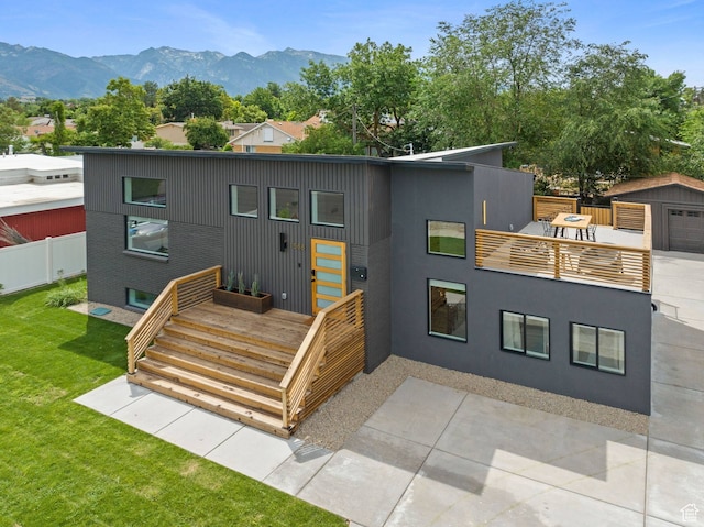 view of front facade with a mountain view, an outdoor structure, a front yard, and a patio area