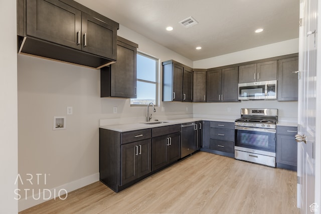 kitchen featuring sink, appliances with stainless steel finishes, dark brown cabinetry, and light wood-type flooring