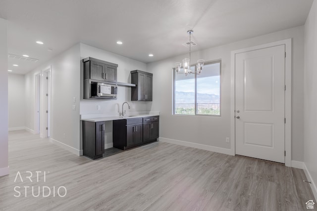 kitchen with pendant lighting, a notable chandelier, sink, and light wood-type flooring