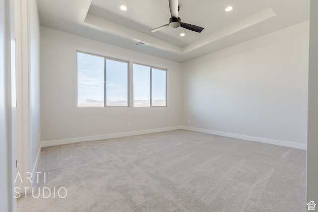 spare room with light colored carpet, a tray ceiling, and ceiling fan