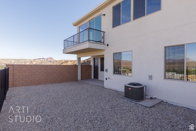 rear view of property featuring a patio area, a mountain view, central AC unit, and a balcony