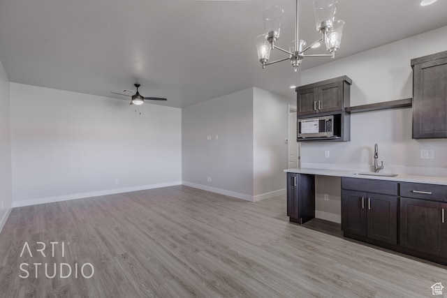 kitchen with light hardwood / wood-style floors, sink, dark brown cabinets, and ceiling fan with notable chandelier