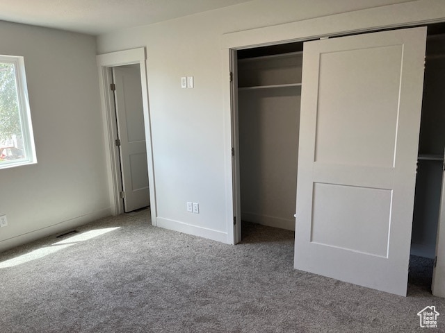 unfurnished bedroom with light carpet and a closet