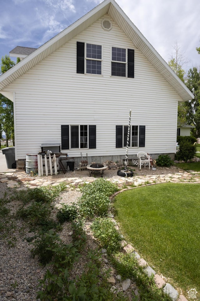 back of property with a lawn and a fire pit