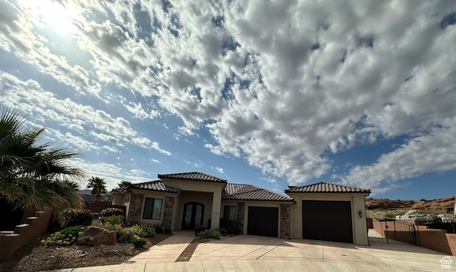 mediterranean / spanish-style house featuring stone siding, concrete driveway, an attached garage, and a tiled roof