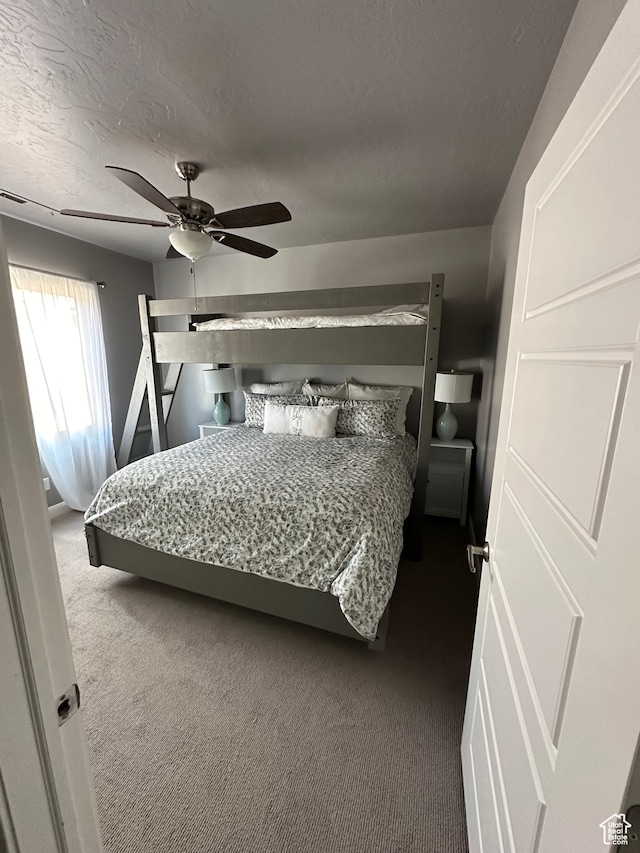 carpeted bedroom featuring a textured ceiling and ceiling fan