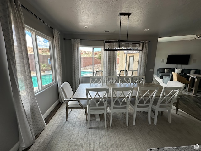 dining space featuring plenty of natural light, a textured ceiling, baseboards, and visible vents