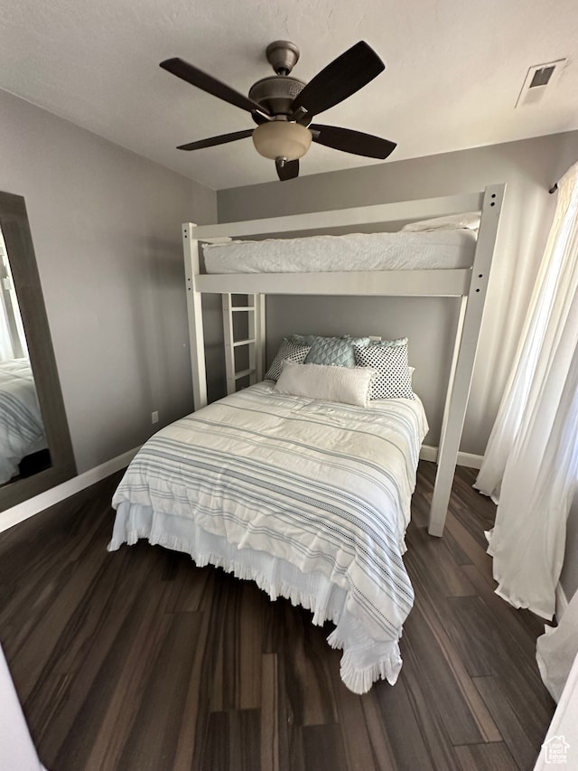 bedroom with ceiling fan, visible vents, baseboards, and wood finished floors