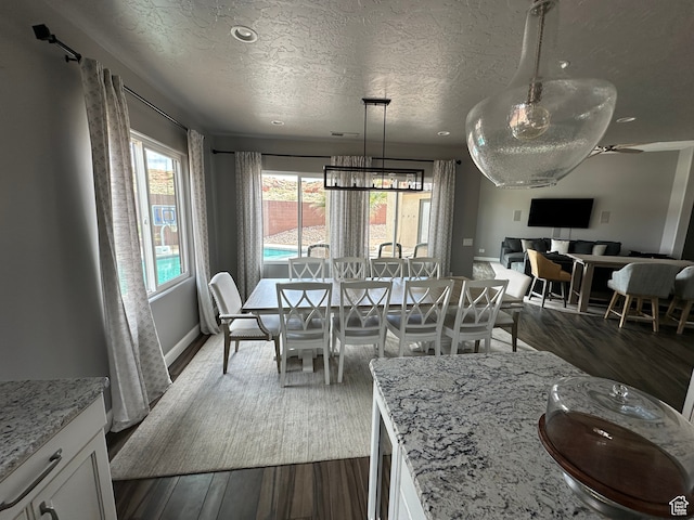 dining space featuring baseboards, dark wood-style flooring, and a textured ceiling