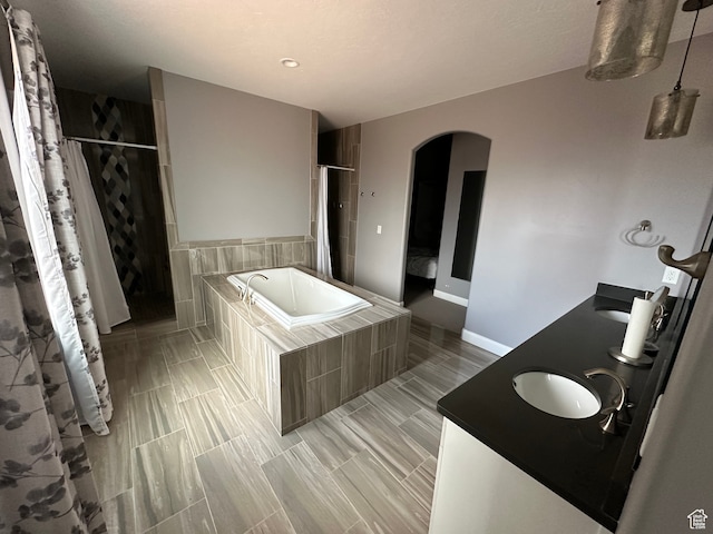 bathroom with baseboards, double vanity, a sink, curtained shower, and a bath
