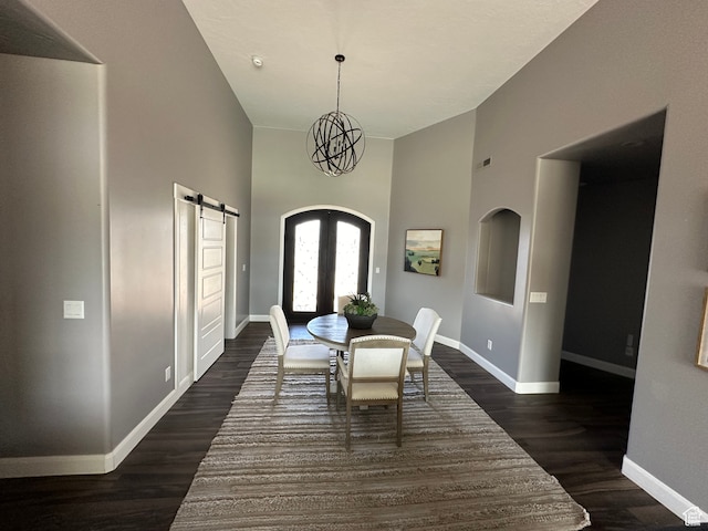 dining room with baseboards, dark wood-style flooring, french doors, a towering ceiling, and a barn door