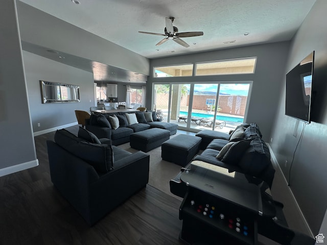 living area featuring visible vents, a ceiling fan, a textured ceiling, baseboards, and dark wood-style flooring