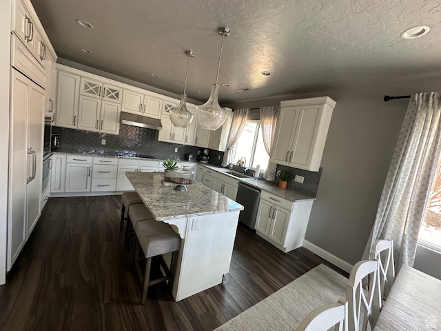 kitchen with under cabinet range hood, a sink, a kitchen island, cooktop, and dishwasher