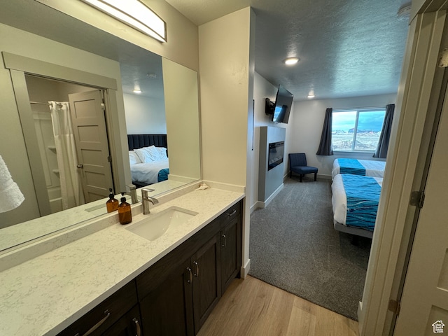 140 W 150 S Unit I32, Garden City, UT 84028 - ensuite bathroom with ensuite bathroom, a textured ceiling, wood finished floors, vanity, and a glass covered fireplace