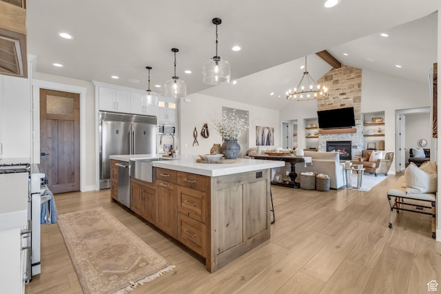 1429 S Hallam Rd Unit 2, Francis, UT 84036 - kitchen with light hardwood / wood-style floors, white cabinetry, a kitchen island with sink, and a fireplace