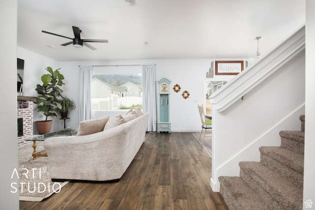 living room featuring ceiling fan, a fireplace, and dark hardwood / wood-style flooring