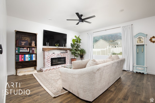 living room featuring ceiling fan, dark hardwood / wood-style floors, and a fireplace