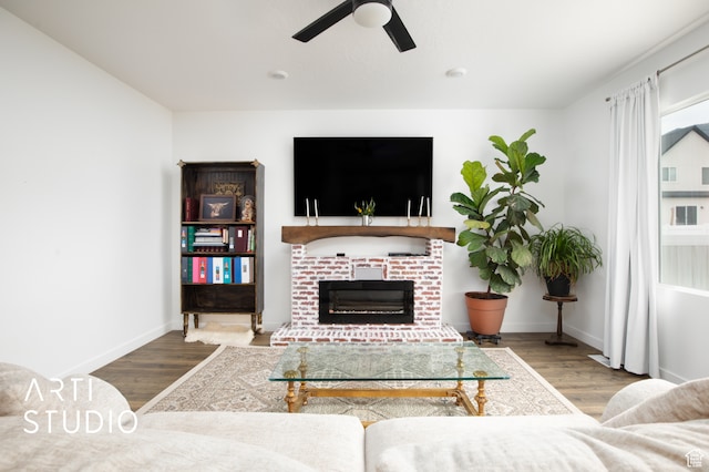 living room featuring a brick fireplace, ceiling fan, and hardwood / wood-style floors