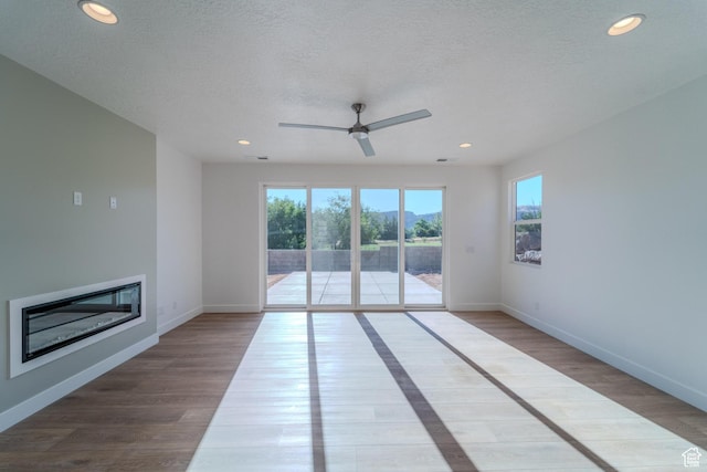 723 S 1220 W Unit 34, Hurricane, UT 84737 - unfurnished living room with recessed lighting, a glass covered fireplace, a textured ceiling, wood finished floors, and baseboards