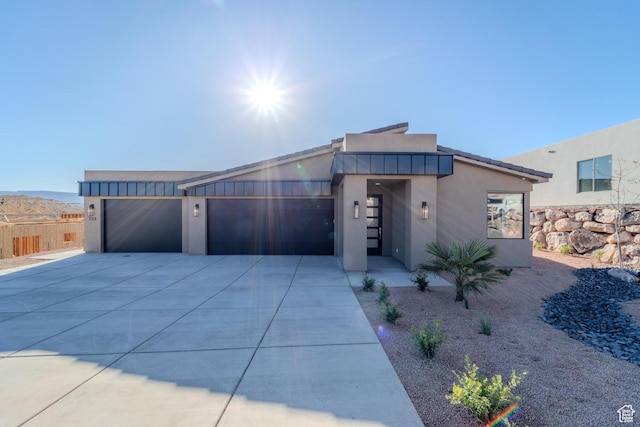 contemporary house featuring stucco siding, concrete driveway, board and batten siding, fence, and a garage