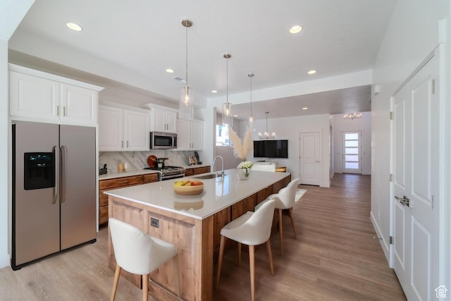 723 S 1220 W Unit 34, Hurricane, UT 84737 - kitchen featuring decorative backsplash, appliances with stainless steel finishes, a kitchen breakfast bar, a kitchen island with sink, and white cabinetry