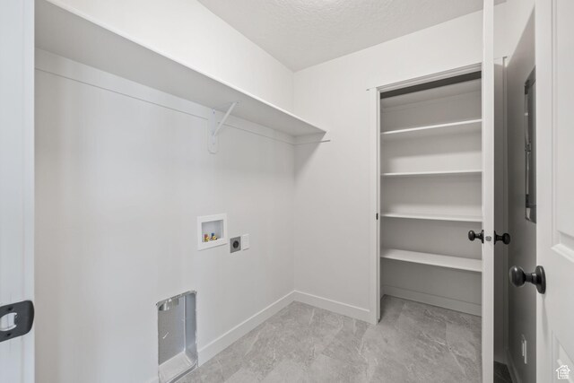 clothes washing area with hookup for an electric dryer, hookup for a washing machine, baseboards, a textured ceiling, and laundry area