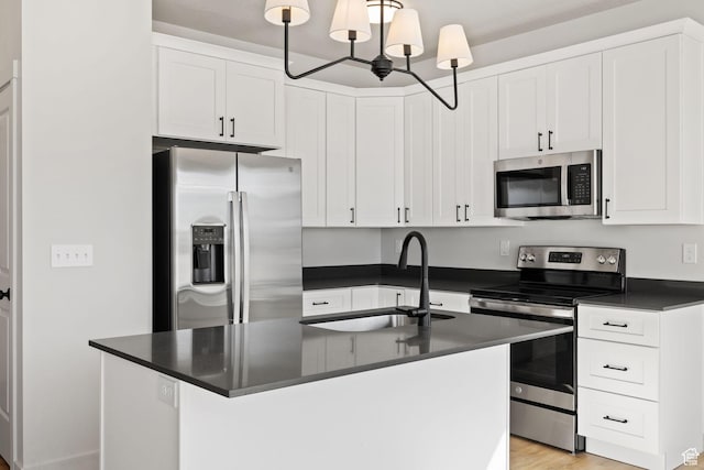 kitchen with a chandelier, a sink, dark countertops, white cabinets, and appliances with stainless steel finishes