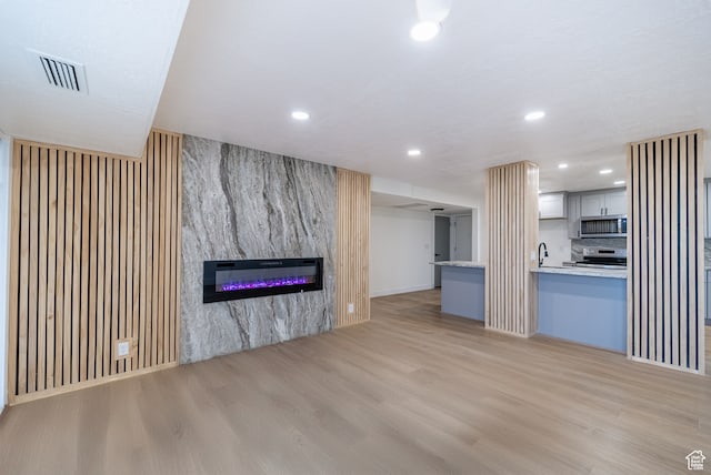 875 S Donner Way Unit 1203, Salt Lake City, UT 84108 - unfurnished living room with light hardwood / wood-style flooring, sink, and a fireplace