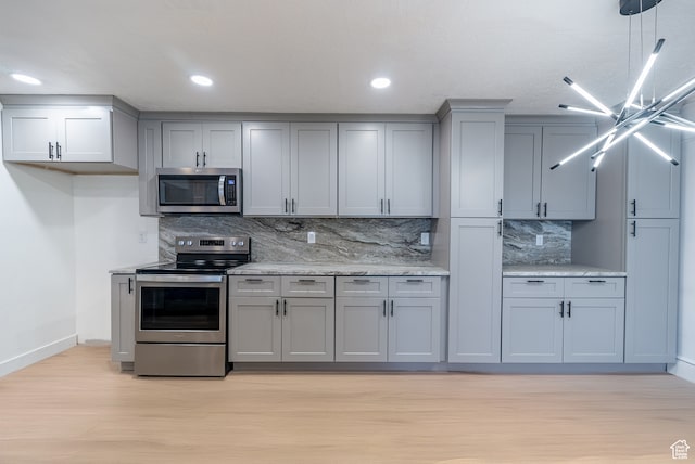 875 S Donner Way Unit 1203, Salt Lake City, UT 84108 - kitchen featuring appliances with stainless steel finishes, tasteful backsplash, light stone counters, gray cabinetry, and light wood-type flooring