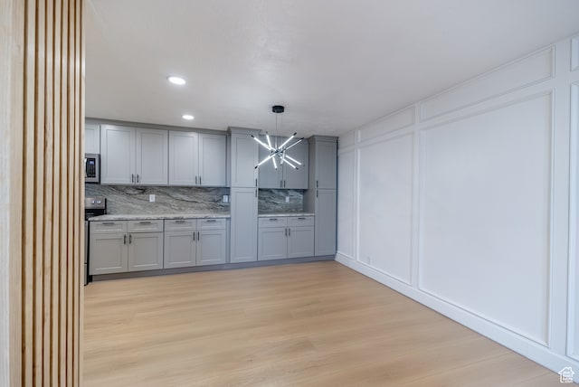 875 S Donner Way Unit 1203, Salt Lake City, UT 84108 - kitchen with stove, hanging light fixtures, gray cabinetry, light hardwood / wood-style flooring, and backsplash