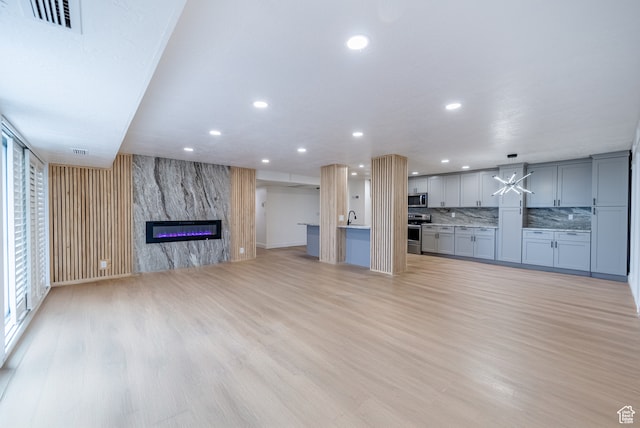 unfurnished living room featuring a high end fireplace, light hardwood / wood-style flooring, and sink