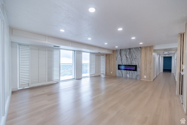 875 S Donner Way Unit 1203, Salt Lake City, UT 84108 - unfurnished living room featuring light wood-type flooring, a fireplace, and a textured ceiling