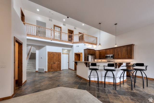 1145 E Bonita St, Moab, UT 84532 - kitchen with dark tile floors, decorative light fixtures, a breakfast bar, stainless steel appliances, and a towering ceiling