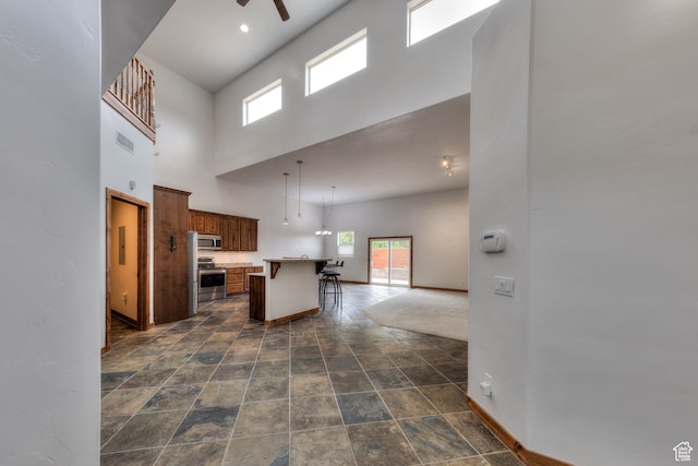 1145 E Bonita St, Moab, UT 84532 - kitchen with appliances with stainless steel finishes, a breakfast bar area, a high ceiling, a center island, and dark tile floors