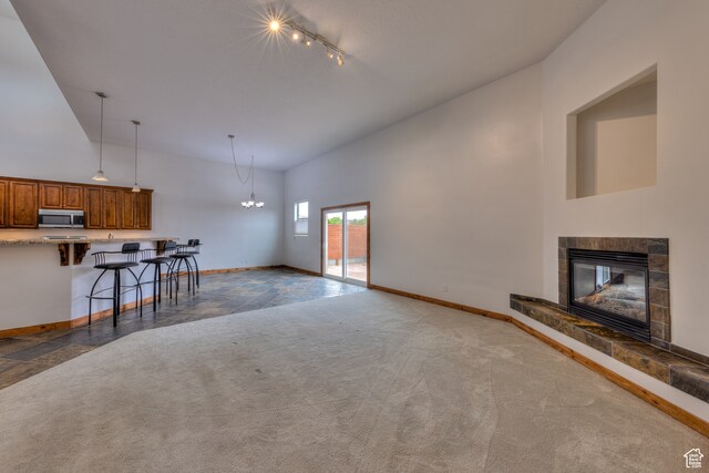 1145 E Bonita St, Moab, UT 84532 - unfurnished living room featuring high vaulted ceiling, dark carpet, and a tiled fireplace