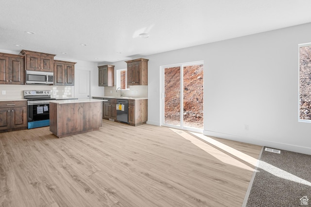 1698 S Marigold Unit 242, Santaquin, UT 84655 - kitchen with stainless steel appliances, light countertops, light wood-style flooring, a center island, and decorative backsplash