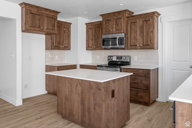 1698 S Marigold Unit 242, Santaquin, UT 84655 - kitchen featuring appliances with stainless steel finishes, light wood-style flooring, tasteful backsplash, baseboards, and a kitchen island