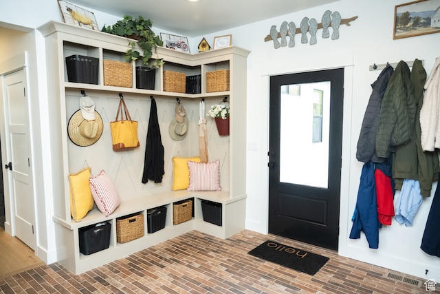mudroom with visible vents and brick floor