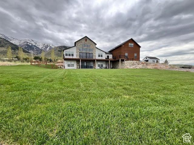 rear view of house featuring a mountain view, a yard, and stone siding