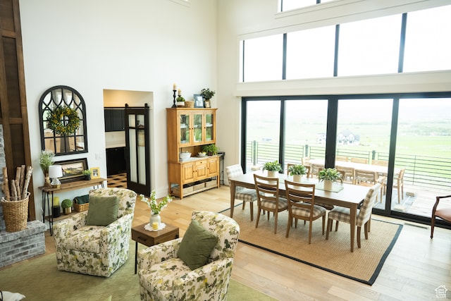 dining space featuring a barn door, light wood-style flooring, and a high ceiling