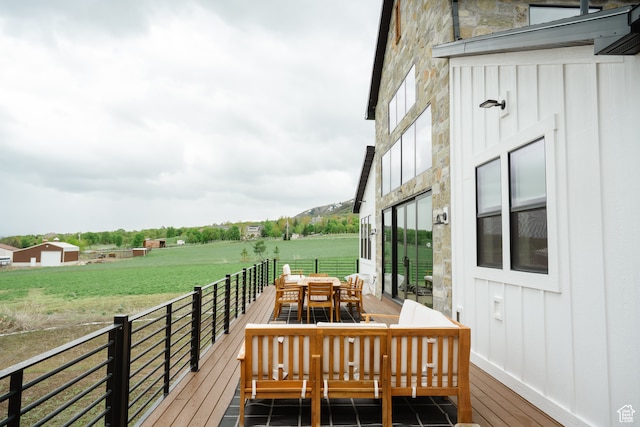 wooden terrace featuring outdoor dining area and a yard