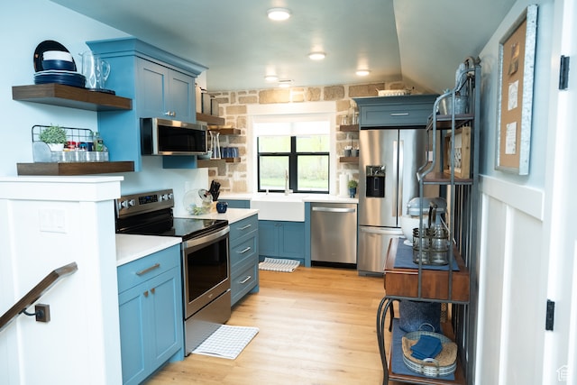 kitchen featuring open shelves, a sink, blue cabinets, and stainless steel appliances