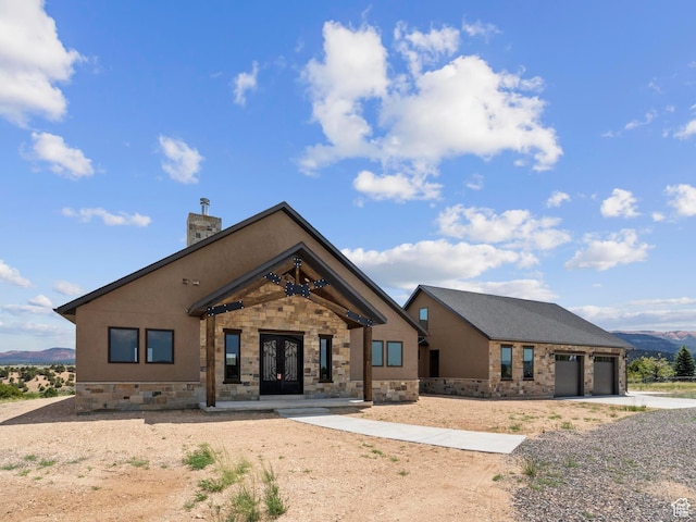 view of front of property featuring french doors, driveway, a mountain view, a garage, and a chimney