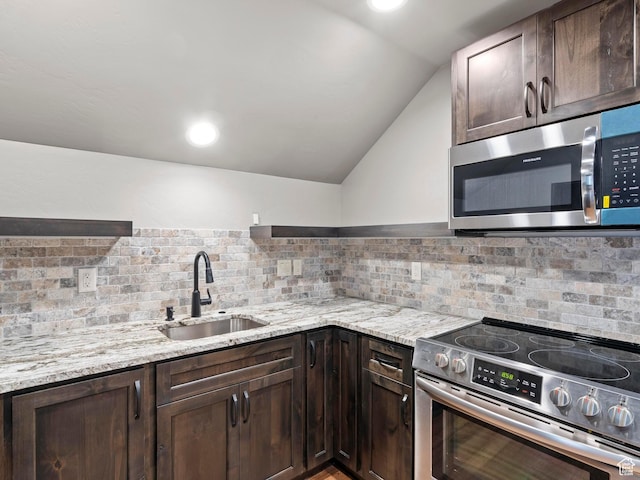 kitchen featuring a sink, dark brown cabinets, appliances with stainless steel finishes, and light stone countertops