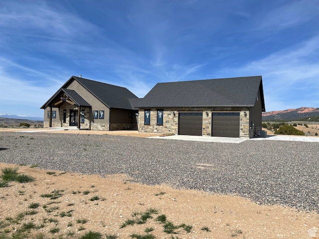 view of front of home featuring stone siding, driveway, a mountain view, and an attached garage